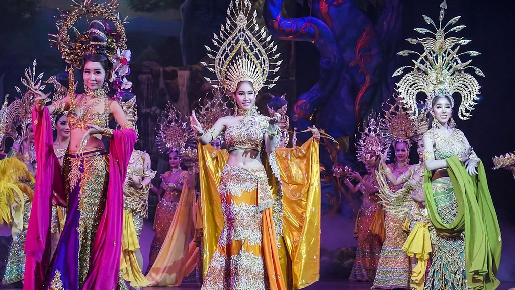 Thai cabaret performers on stage in gold headdresses and silk
